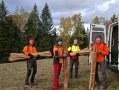 vier Männer stehen mit Holzpfählen vor einer offenen Hecktür eines Transporters