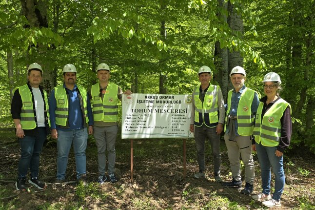 5 Männer und eine Frau stehen in gelben Warnwesten vor einem weißen Schild mit türkischem Text im Wald (Foto: M. Seho)